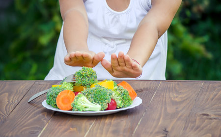The child eats vegetables in summer. Selective focus. People.の写真素材