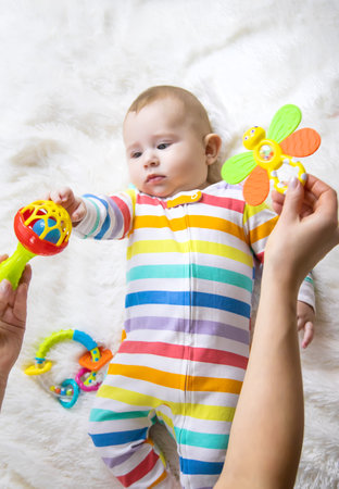 The mother gives a rattle to the baby. Selective focus. child.