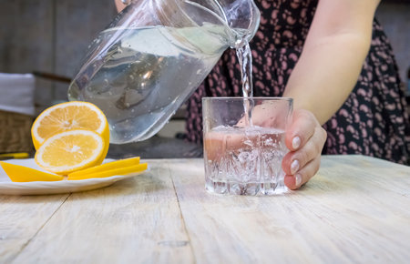 The girl pours water with lemon. Selective focus. Drink.の写真素材
