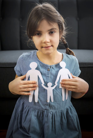 Child with a paper family in his hands. the concept of divorce, custody and child abuse. Selective focus. People.の写真素材