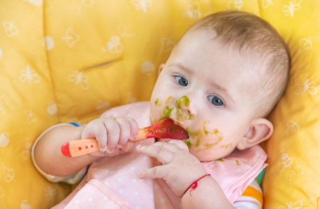 Little baby is eating broccoli vegetable puree. Selective focus. People.の写真素材