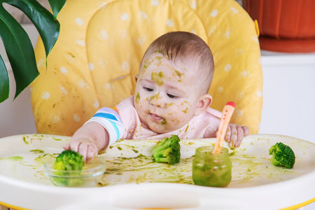 Little baby eats broccoli puree himself. Selective focus. People.の写真素材
