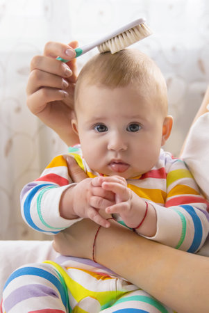 The mother is combing the little baby's hair. Selective focus. People.の写真素材