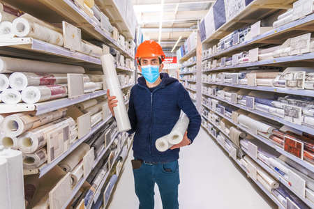 A man in a hardware store. Wallpaper for sale. Selective focus. People.