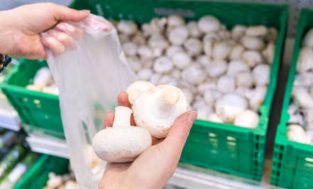 A woman chooses champignons mushrooms in a supermarket. Selective focus. Food.の写真素材