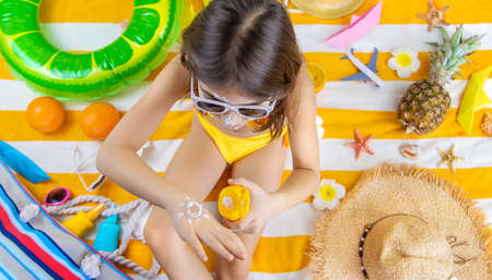 A child girl smears sunscreen on her skin. Selective focus. Kid.