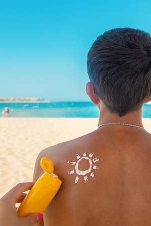 The girl on the beach applies sunscreen to the skin of a man. Selective focus. nature.