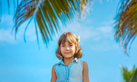 Child girl on the background of palm trees and ocean. Selective focus.の写真素材