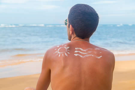 A man on the beach with sunscreen on his back. Selective focus. Travel.