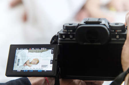Baby sleeps on a white bed. father takes pictures, Selective focus. Child.の写真素材