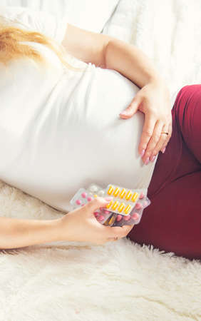 A pregnant woman holds many pills in her hands. Selective Focus. people.の写真素材