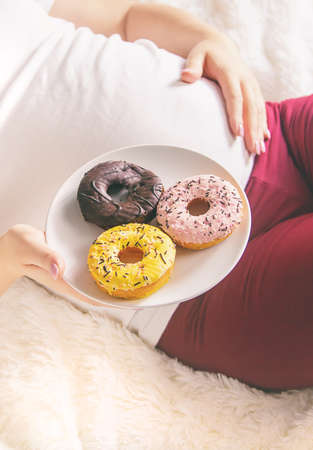 A pregnant woman eats sweet donuts. Selective Focus. Food.の写真素材