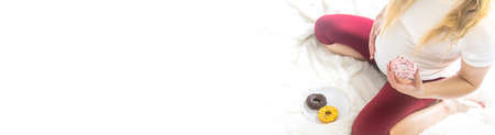A pregnant woman eats sweet donuts. Selective Focus. Food.の写真素材