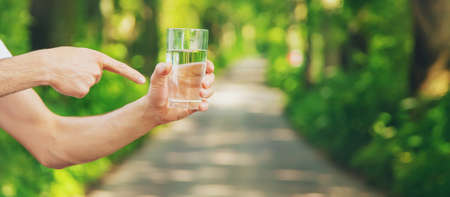 A man drinks water from a glass on the nature. Selective focus. Drink.
