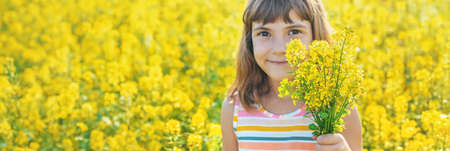 A child in a yellow field, mustard blooms. Selective focus.