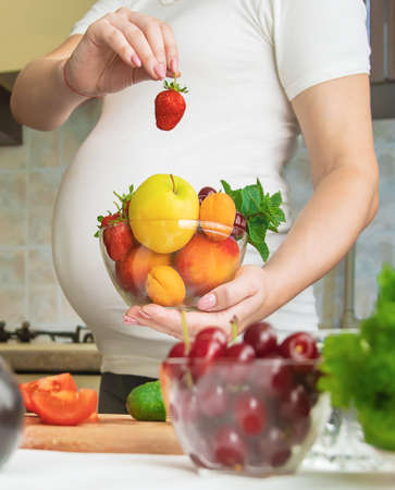 A pregnant woman eats vegetables and fruits. Selective focus. Food.の写真素材