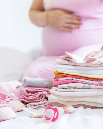 A pregnant woman is folding baby things. Selective focus. people.