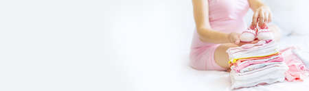 A pregnant woman is folding baby things. Selective focus. people.の写真素材