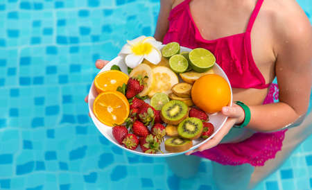 The child eats fruit near the pool. Selective focus. Kid.の写真素材