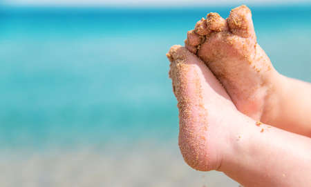 Baby feet on the background of the sea. Selective focus. People.
