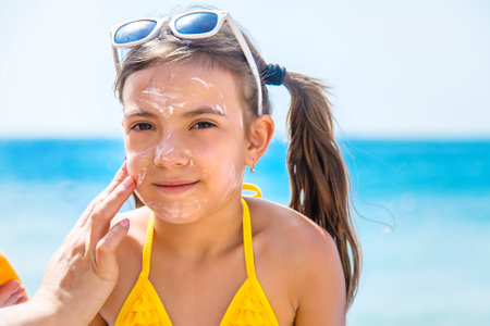 The child is smearing sunscreen on the mother. Selective focus. Nature.