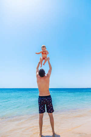 The father tosses the baby against the background of the sea. Selective focus. Child.の写真素材