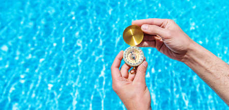 Compass in the hands of a man against the background of water. Selective focus. People.の写真素材