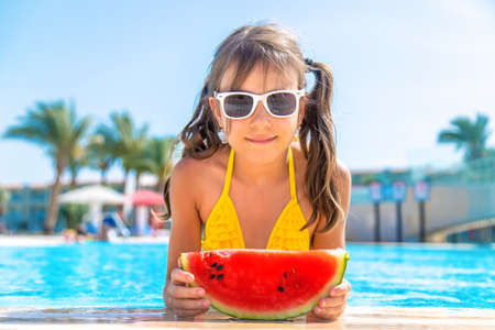 Child girl eats watermelon near the pool. Selective focus. Kid.の写真素材