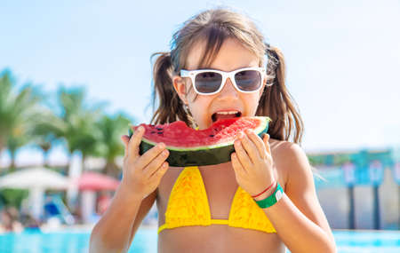 Child girl eats watermelon near the pool. Selective focus. Kid.の写真素材