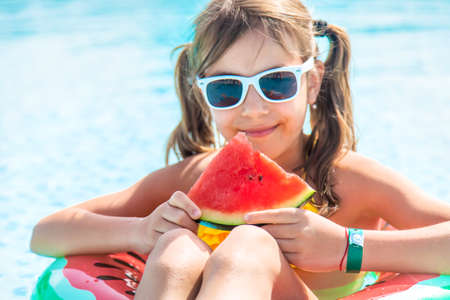 Child girl eats watermelon near the pool. Selective focus. Kid.の写真素材