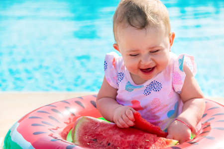 Baby girl eats watermelon near the pool. Selective focus. Kid.の写真素材