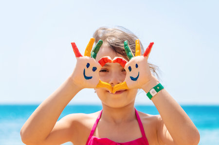 On the hands of the child, a smile with paints on the sea. Selective focus. Kid.の写真素材