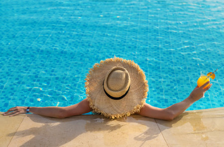 Woman with cocktail in the pool. Selective focus. Drink.