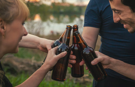 Bottles with beer in the hands of young people in nature. Selective focus. Nature.