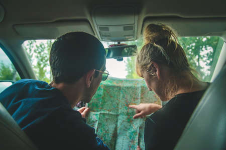 A man and a woman in the car looks at the map. Selective focus. People.