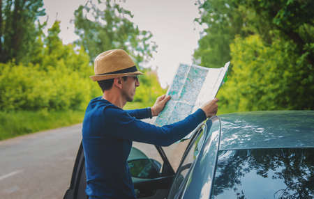 The man in the car looks at the map. Selective focus. People.