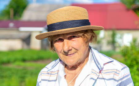 Farmer grandmother in a hat in the garden. Selective focus. People.の写真素材