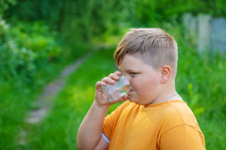 Child boy drinks water from a glass. Selective focus. Kid.の写真素材