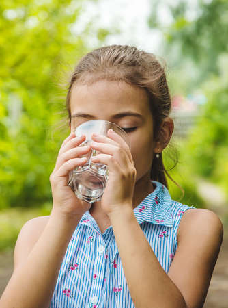 Child girl drinks water from a glass. Selective focus. Kid.の写真素材