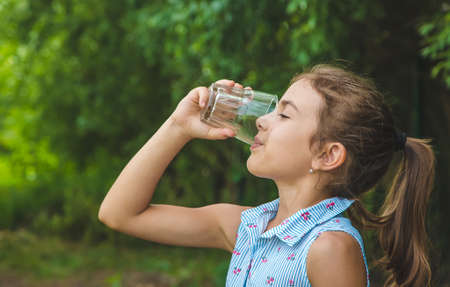Child girl drinks water from a glass. Selective focus. Kid.の写真素材