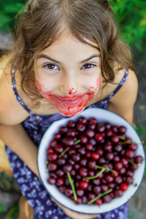 The child eats cherries in the garden. Selective focus. Food.の写真素材