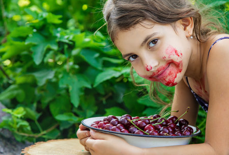 The child eats cherries in the garden. Selective focus. Food.の写真素材