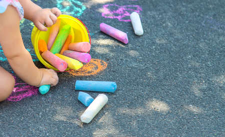 The child draws with chalk on the asphalt. Selective focus. Kids.の写真素材