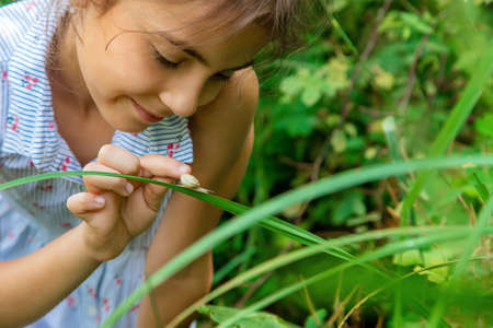 The child looks at the snail through a magnifying glass. Selective focus. Nature.