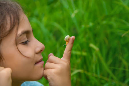 The child looks at the snail through a magnifying glass. Selective focus. Nature.の写真素材