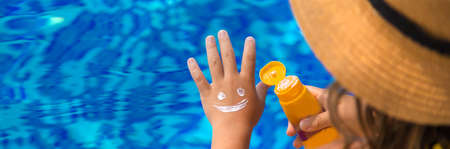 The child smears sunscreen on her hand. Selective focus. Kid.の写真素材
