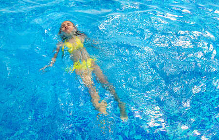 The child swims on its back in the pool. Selective focus. Kid.の写真素材