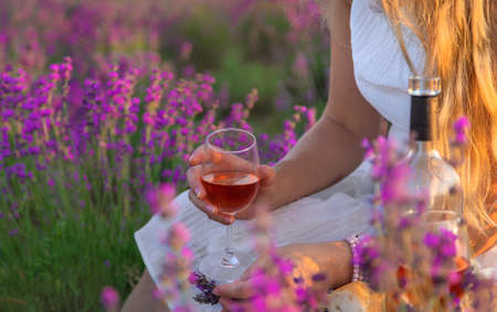 A woman holds wine in glasses. Picnic in the lavender field. Selective focus. nature.の写真素材