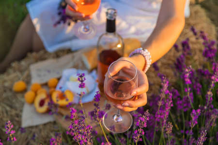 A woman holds wine in glasses. Picnic in the lavender field. Selective focus. nature.