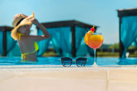 Woman with cocktail near the pool. Selective focus. Drink.の写真素材